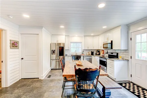 a kitchen with a dining table chairs and refrigerator