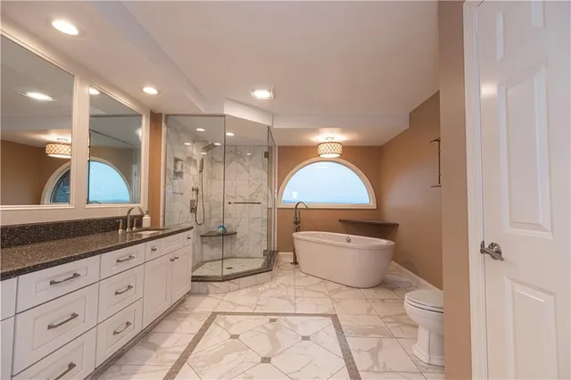 a large bathroom with a granite countertop sink a toilet a large mirror and a shower