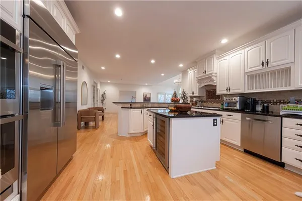 a kitchen with stainless steel appliances granite countertop a refrigerator a stove and a wooden floors