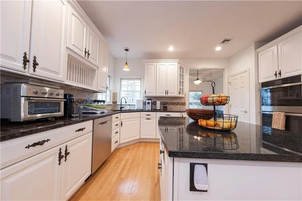 a kitchen with stainless steel appliances granite countertop a sink dishwasher a stove and a microwave oven with cabinets