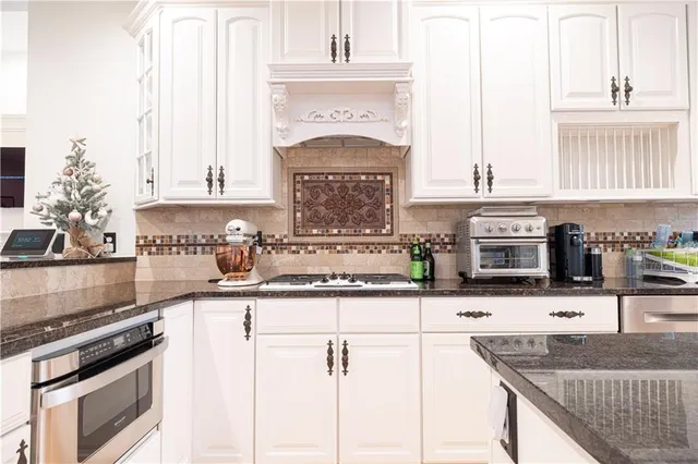 a kitchen with granite countertop a stove a sink and a microwave