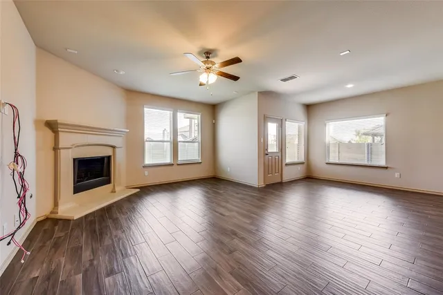 a view of an empty room with a fireplace and wooden floor