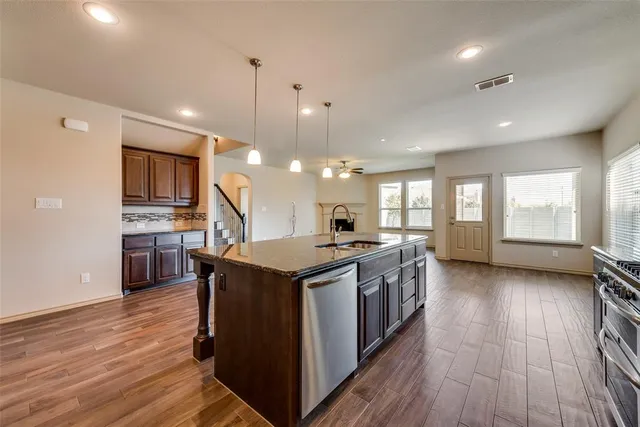 a kitchen with kitchen island a stove a sink a refrigerator cabinets and wooden floor