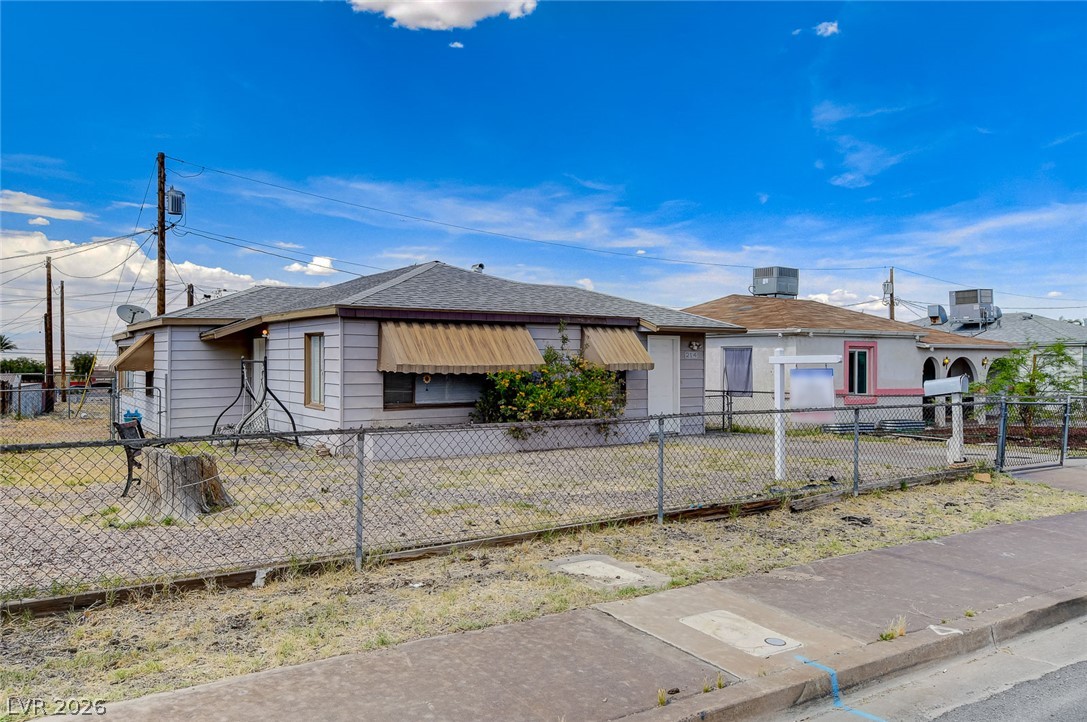 214 West Victory Road Henderson, NV 89015 - Photo 29 of 33 A modest dwelling with awnings over its front windows, secured by a chain-link fence.
