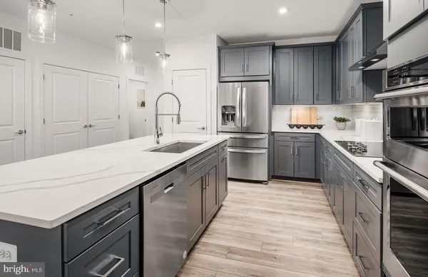 a kitchen with kitchen island granite countertop a sink stainless steel appliances and cabinets