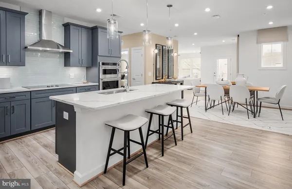 a large kitchen with cabinets chairs and wooden floor