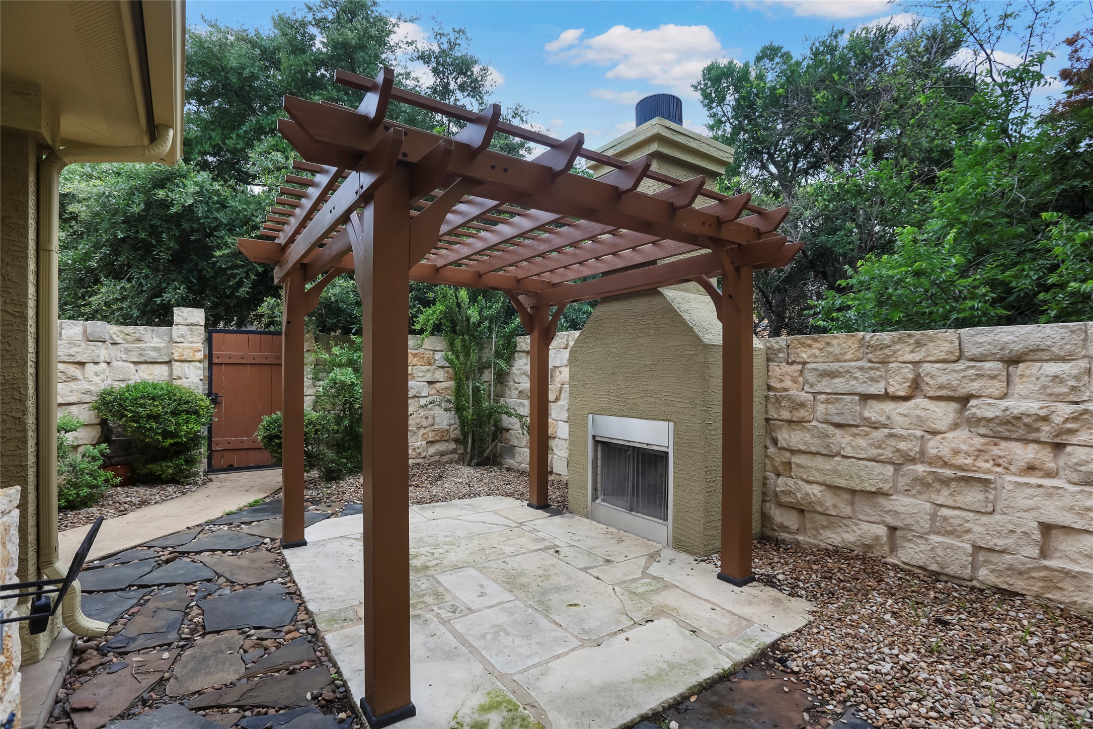 3406 Menchaca Road, Unit 19 Austin, TX 78704 - Photo 4 of 25 A stone patio area features a handsome wood pergola alongside an outdoor fireplace.