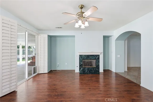an empty room with wooden floor fireplace and windows