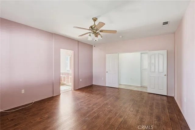 an empty room with wooden floor ceiling fan and windows