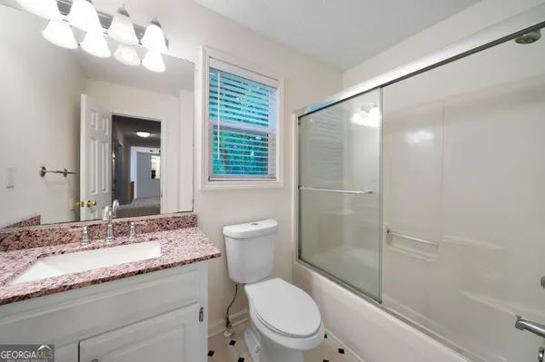 a bathroom with a granite countertop sink toilet a mirror and shower