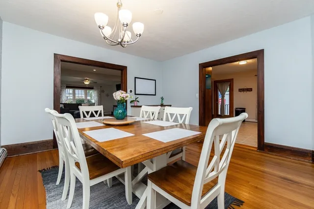 a dining room with wooden floor a chandelier a wooden table and chairs