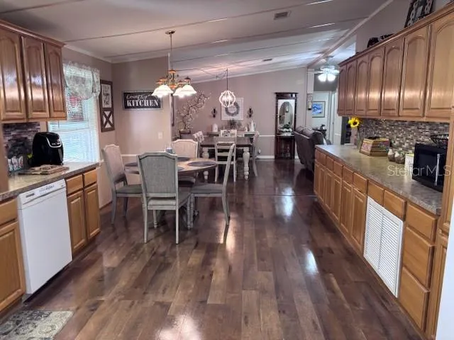 a kitchen with stainless steel appliances granite countertop a refrigerator a stove top oven a dining table and chairs with wooden floor