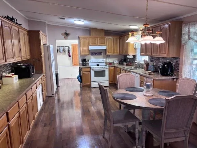 a kitchen with stainless steel appliances a dining table chairs stove refrigerator and cabinets