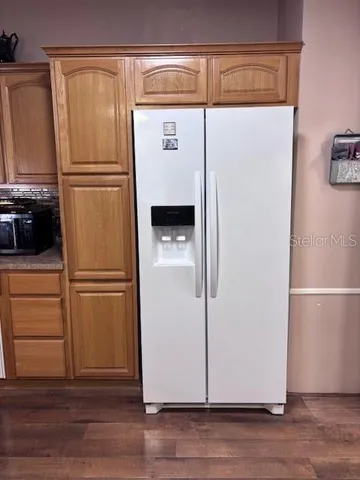 a white refrigerator freezer and a wooden floor