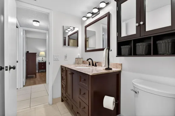 a bathroom with a granite countertop sink vanity mirror and toilet