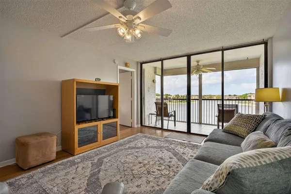 a living room with furniture a flat screen tv and a floor to ceiling window