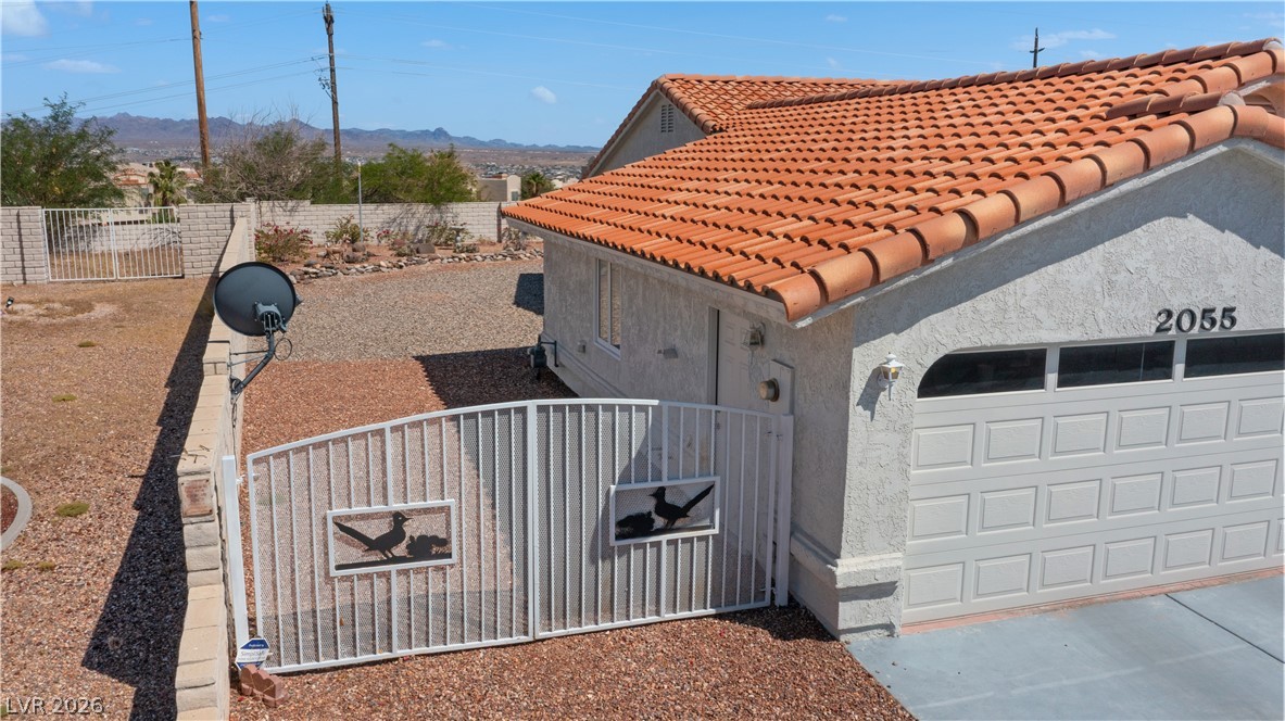 2055 Cholla Way Laughlin, NV 89029 - Photo 71 of 87 A terracotta-tiled roof crowns this stucco residence, featuring a secure gated entry and an attached garage.