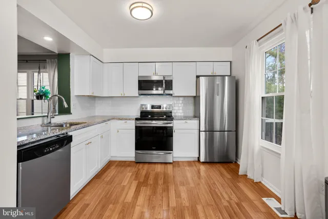a kitchen with a refrigerator a sink dishwasher and a stove top oven with wooden floor