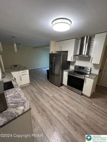 a kitchen with stainless steel appliances kitchen island granite countertop a stove and a refrigerator