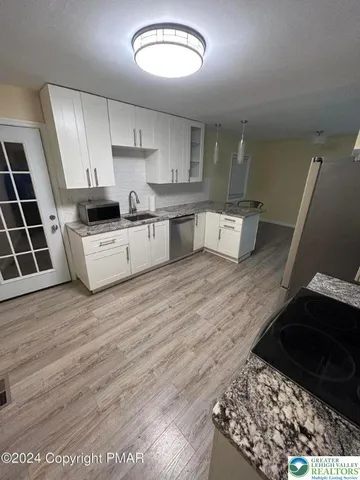 a large white kitchen with wooden floors and stainless steel appliances