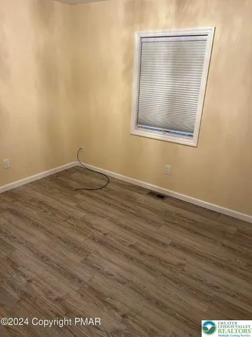 an empty room with wooden floor and mirror