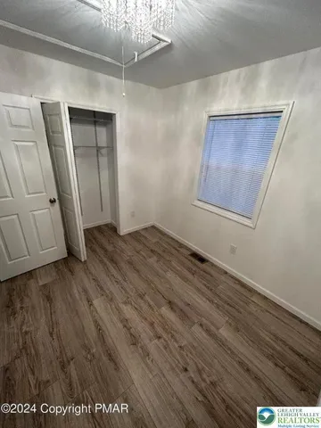 a view of an empty room with wooden floor and staircase
