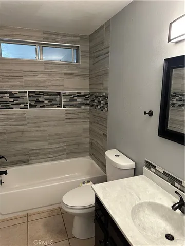 a bathroom with a granite countertop toilet sink and mirror