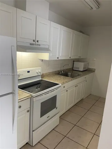 a kitchen with granite countertop white cabinets and white appliances