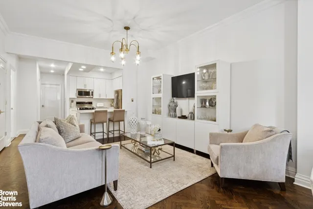 a living room with furniture kitchen view and a chandelier