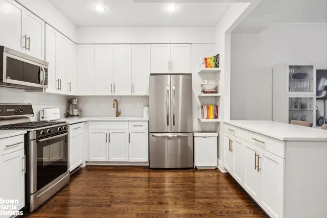 a kitchen with stainless steel appliances granite countertop a refrigerator stove a sink and white cabinets