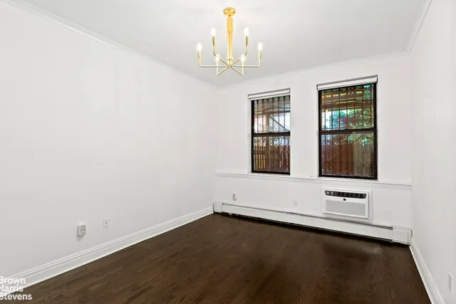 an empty room with wooden floor cabinet and windows