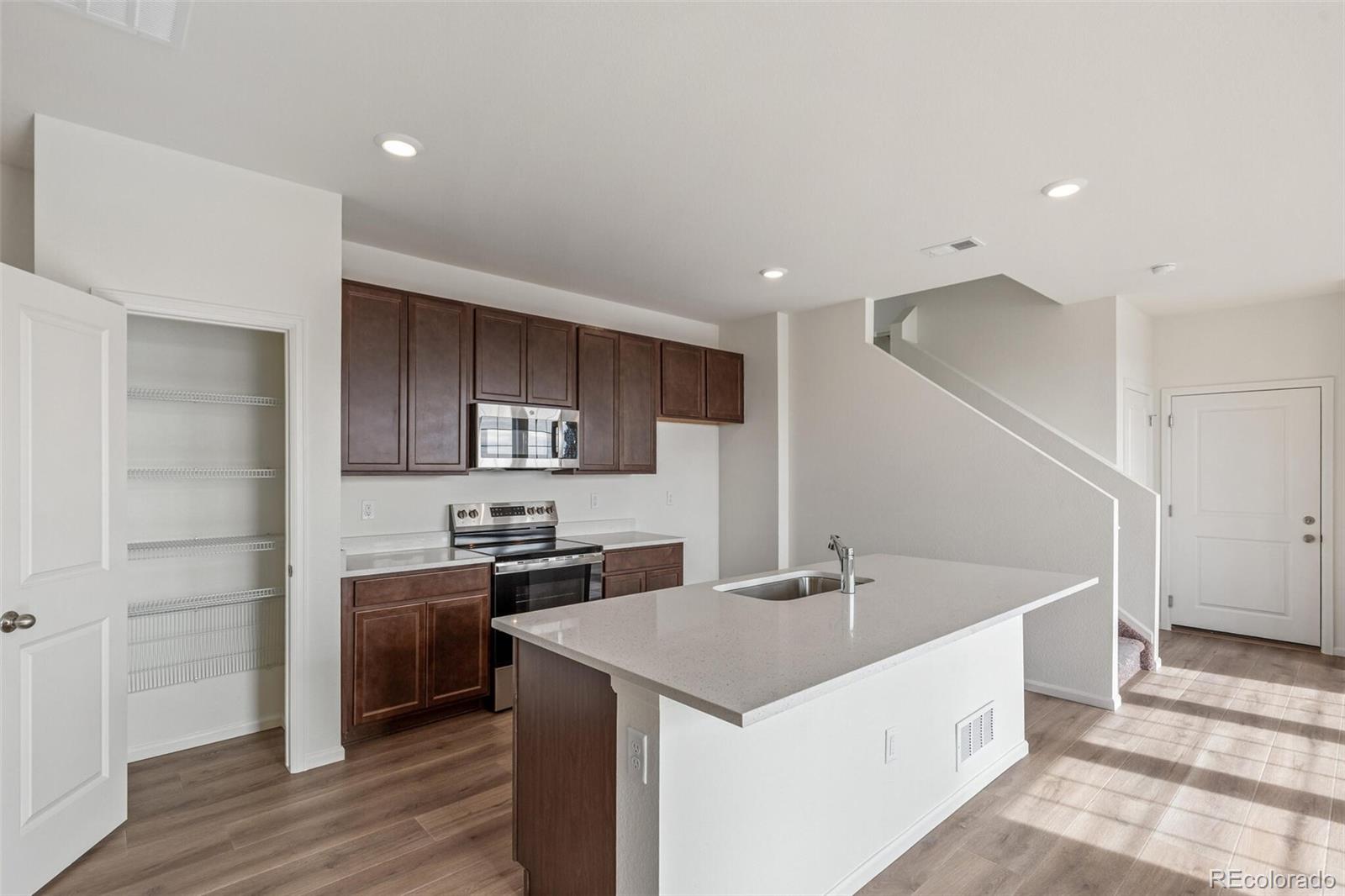 28636 East 6th Place Watkins, CO 80137 - Photo 11 of 32 a kitchen with stainless steel appliances a sink a stove a refrigerator and cabinets