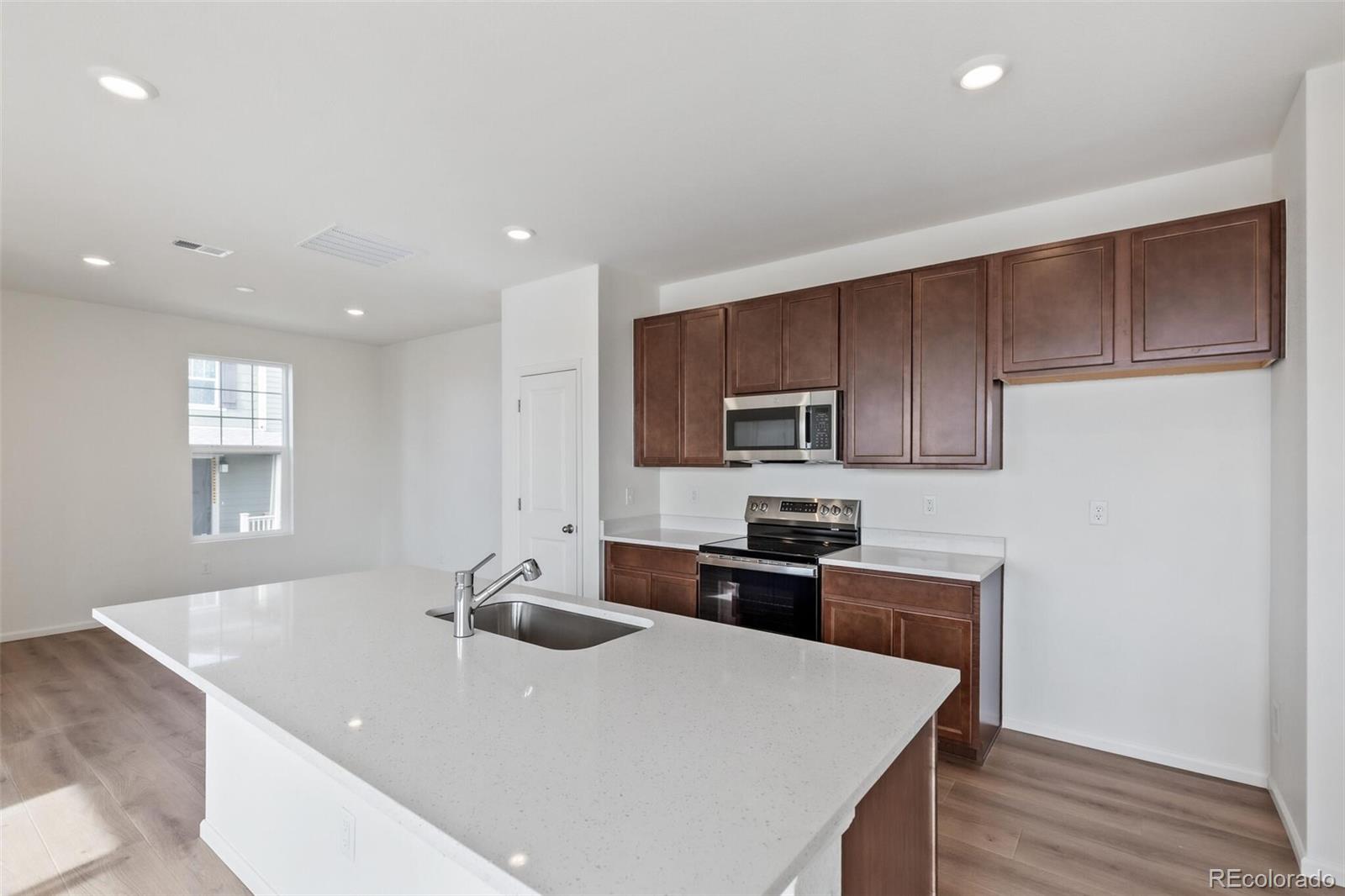 28636 East 6th Place Watkins, CO 80137 - Photo 13 of 32 a kitchen with stainless steel appliances granite countertop a sink a stove a refrigerator cabinets and a window