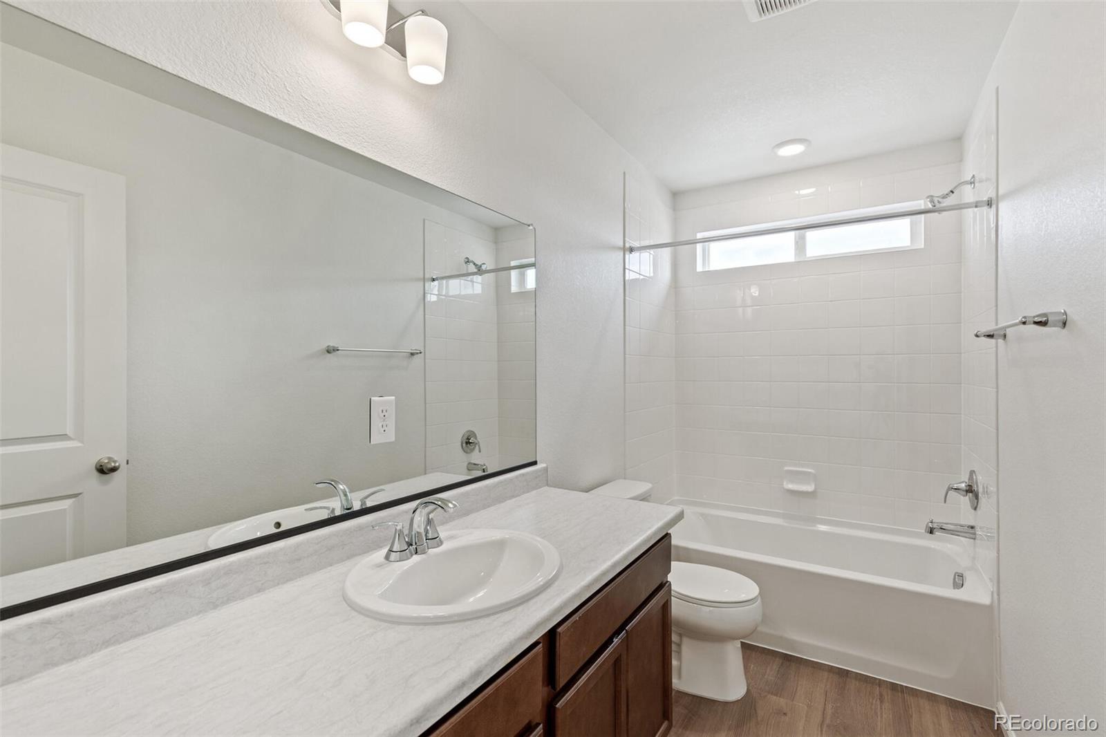28636 East 6th Place Watkins, CO 80137 - Photo 25 of 32 a bathroom with a granite countertop sink a toilet and shower