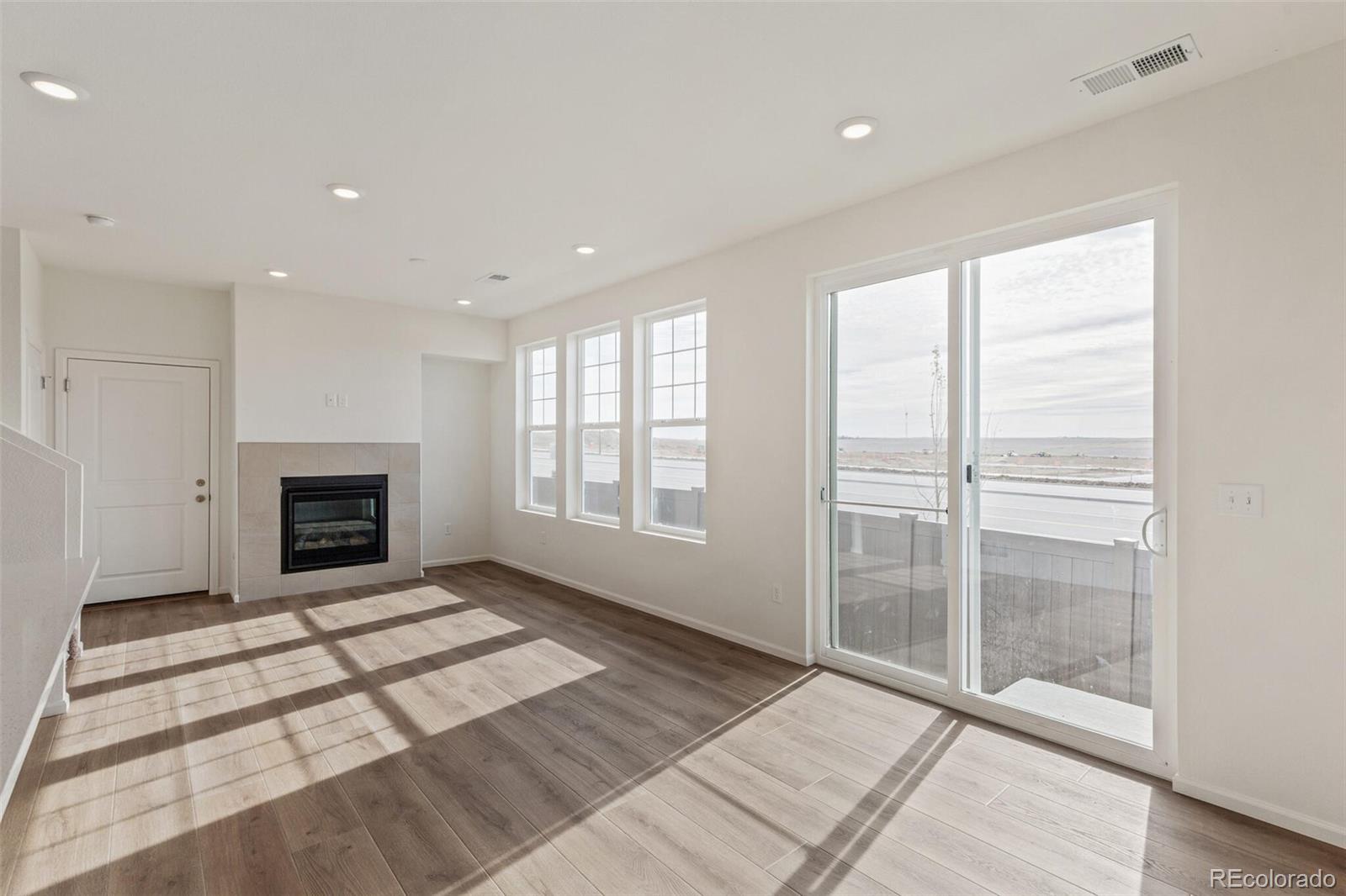 28636 East 6th Place Watkins, CO 80137 - Photo 5 of 32 a view of an empty room with glass door and windows