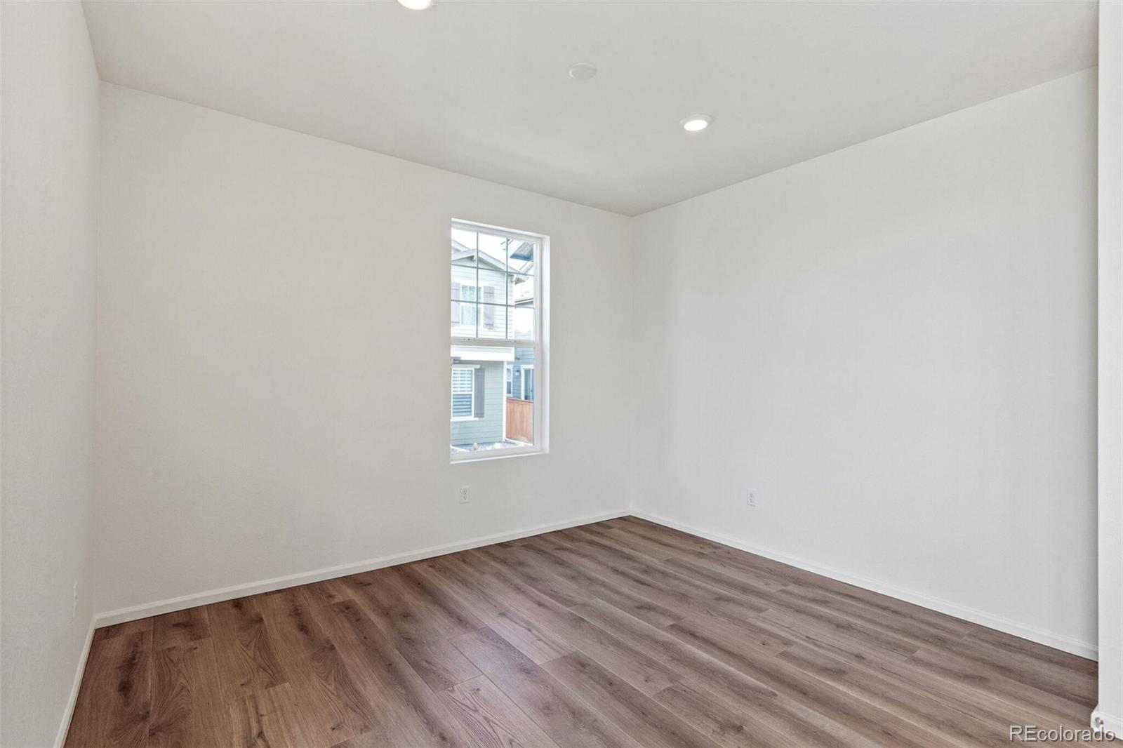 28636 East 6th Place Watkins, CO 80137 - Photo 7 of 32 an empty room with wooden floor and windows
