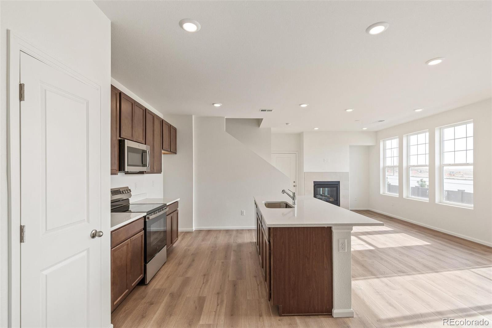 28636 East 6th Place Watkins, CO 80137 - Photo 9 of 32 a kitchen with granite countertop kitchen island wooden floors granite counter tops and a window