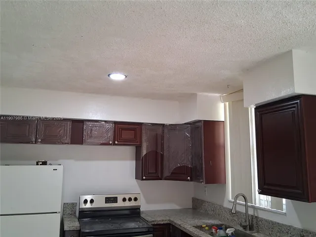 a kitchen with a refrigerator and a stove top oven