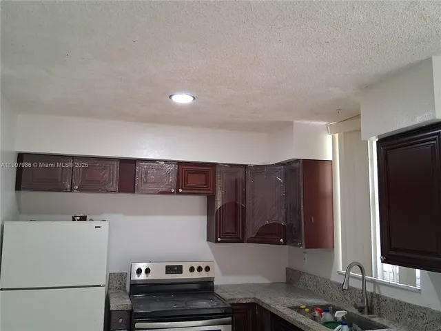 a kitchen with a refrigerator and a stove top oven
