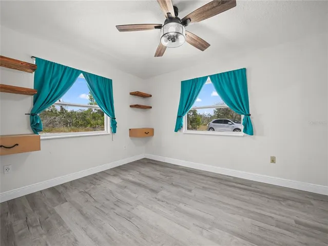 an empty room with window ceiling fan and wooden floor