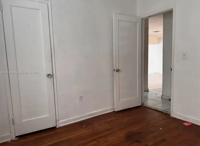 a view of an empty room with wooden floor and closet