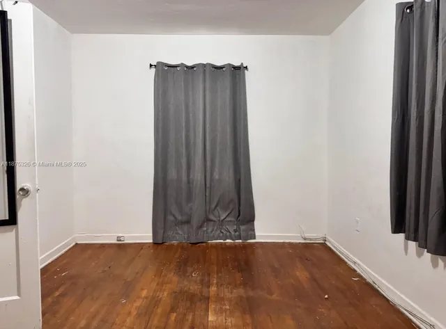 an empty room with wooden floor and cabinet