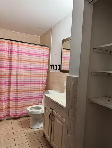 a bathroom with a granite countertop toilet a sink a mirror and shower curtain