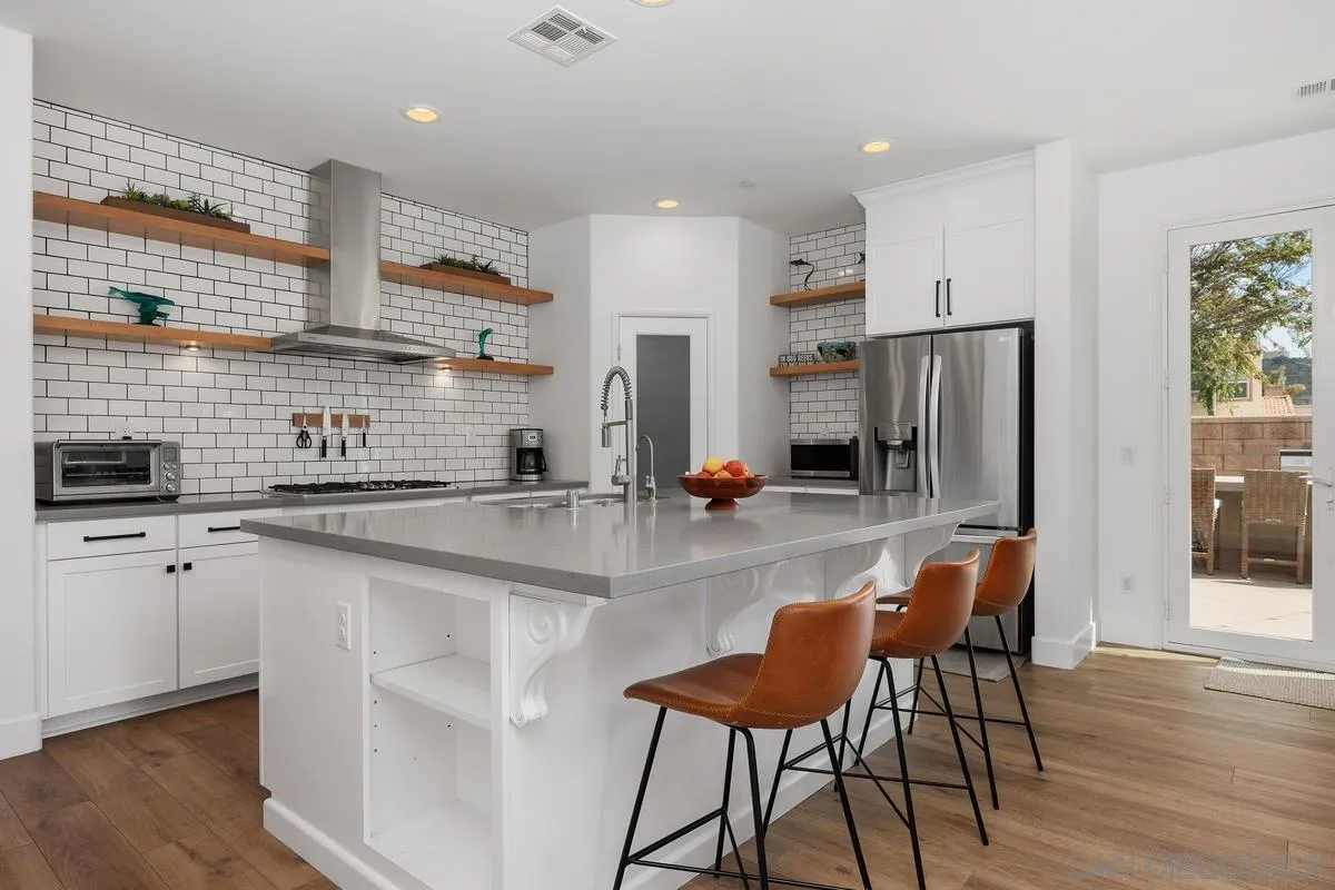 3741 Bergen Peak Place Carlsbad, CA 92010 - Photo 8 of 39 a kitchen with stainless steel appliances granite countertop a stove top oven a sink a refrigerator white cabinets and wooden floor