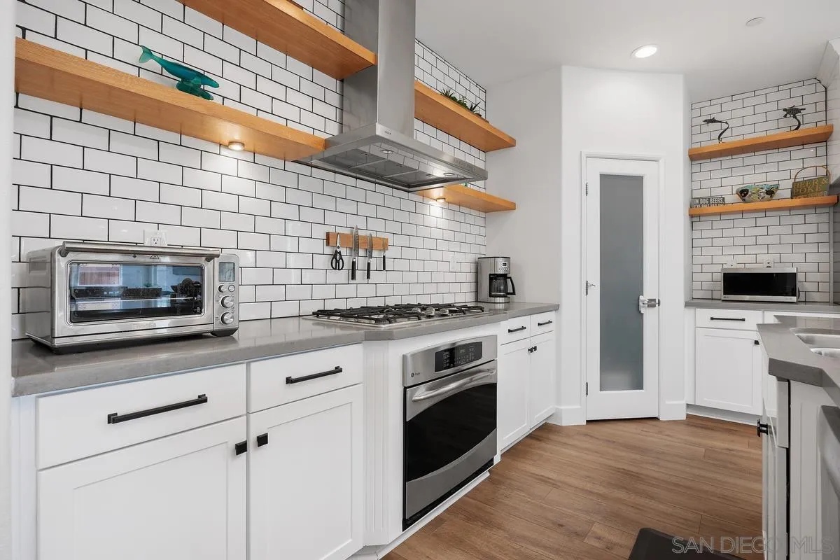 3741 Bergen Peak Place Carlsbad, CA 92010 - Photo 9 of 39 a kitchen with stainless steel appliances white cabinets and a stove top oven