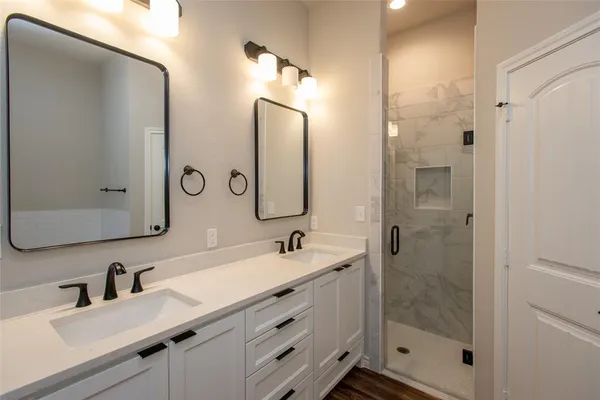 a bathroom with a double vanity sink mirror double shower and a mirror