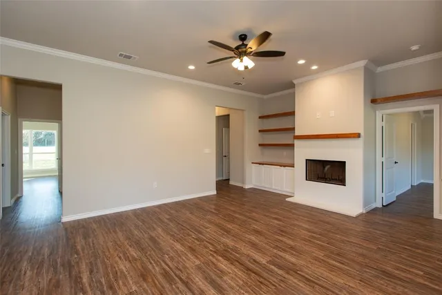 a view of an empty room with wooden floor fireplace and a window