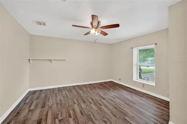 a view of empty room with wooden floor and fan