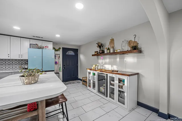 a kitchen with stainless steel appliances a dining table chairs and cabinets