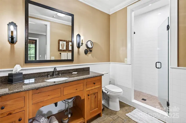 a bathroom with a granite countertop sink a toilet a mirror and shower